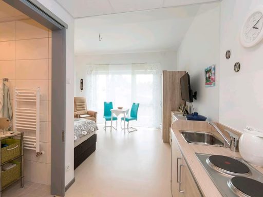 Helle Wohnung mit Küche, Essbereich und Wohnzimmer, großen Fenstern und moderner Einrichtung.